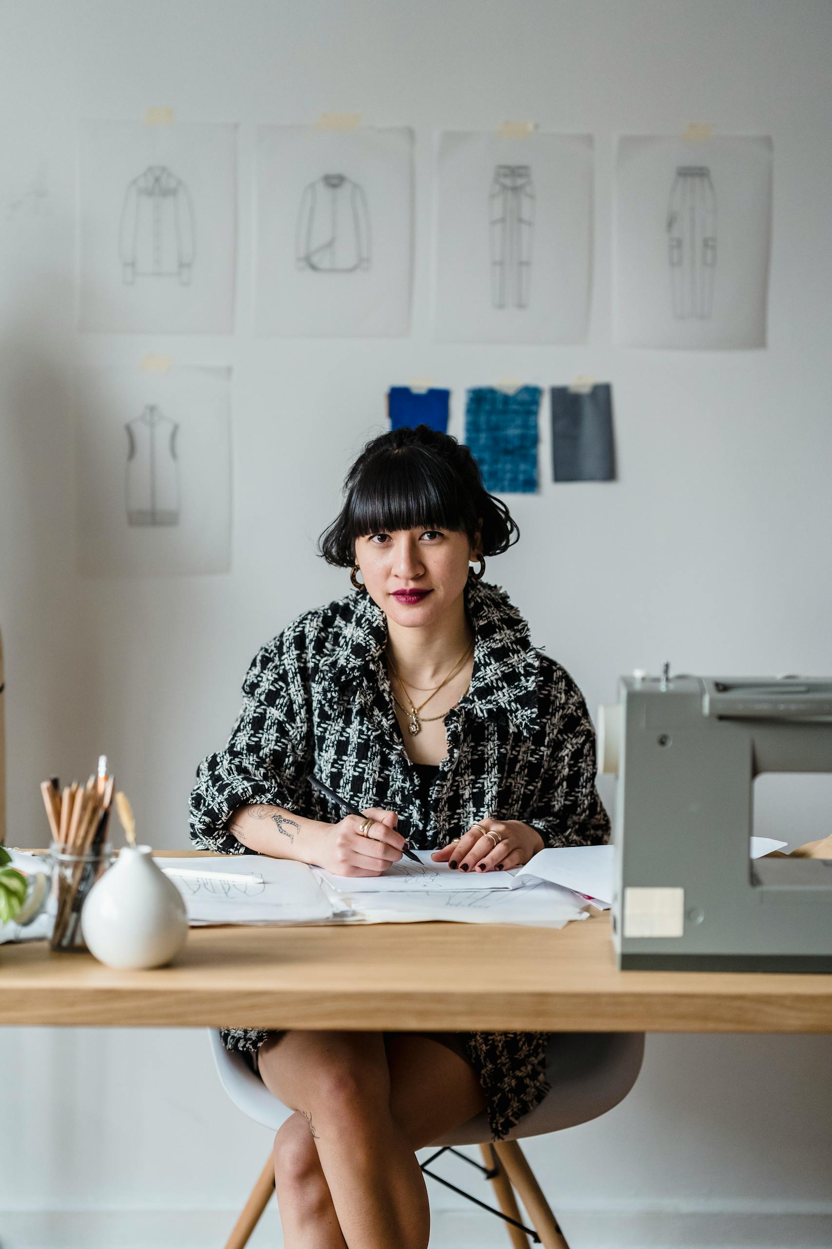 An artisan fashion designer sketching clothing designs in her creative workspace.
