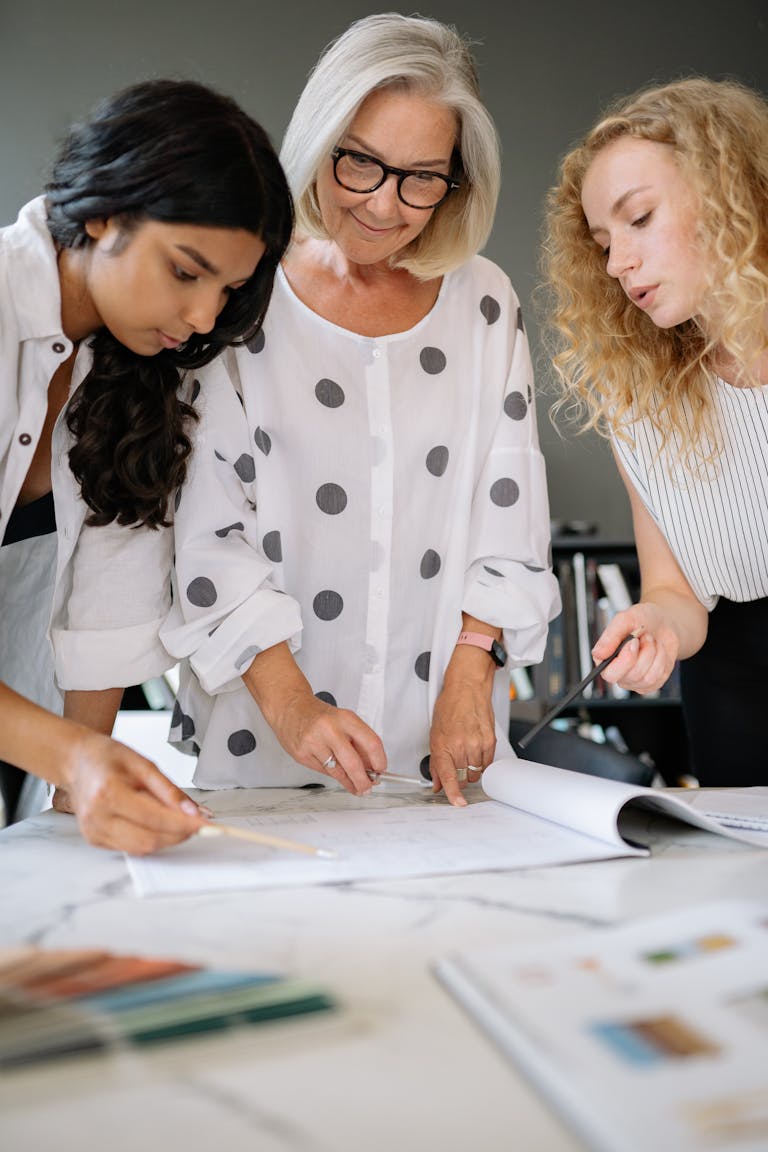 Three diverse women actively collaborating on a project in a modern office setting, emphasizing teamwork.